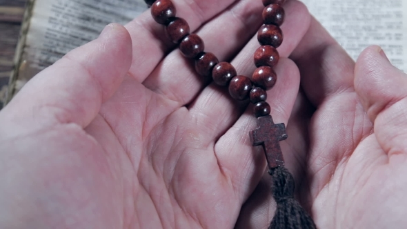 Hands Holding The Bible And Praying With a Rosary