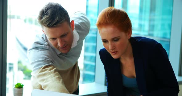 Executives discussing over laptop