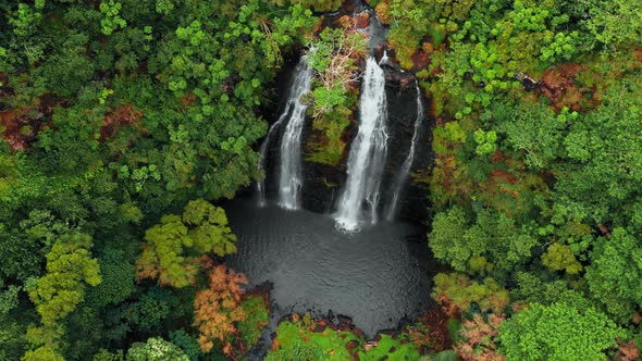 Drone moves away from a mountain waterfall in an autumn forest, Opaekaa Falls, Kauai, Hawaii, USA