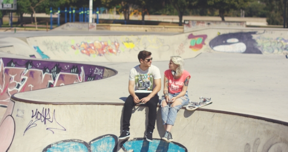 Young Couple Sitting On a Wall At a Skate Park