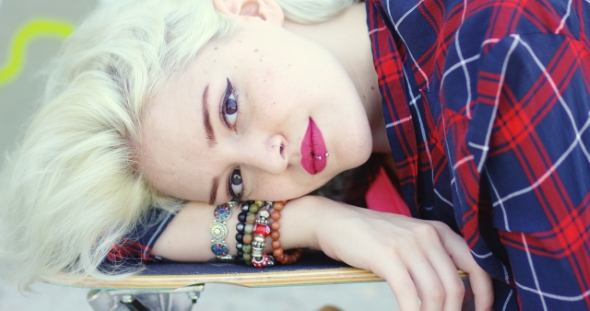 Hipster Young Woman Lying On a Skate Board