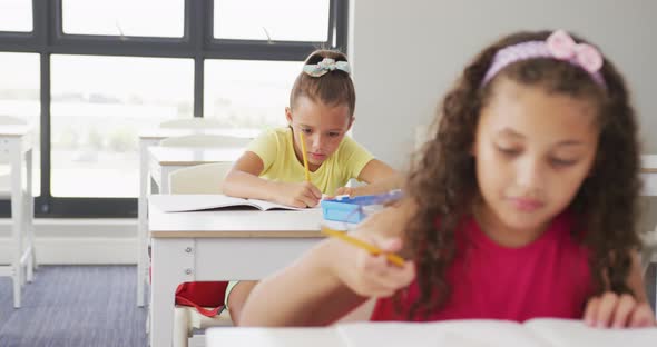 Video of focused diverse girls sitting at school desks and learning