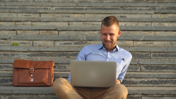 Young Man Sitting On The Stairs Using Laptop