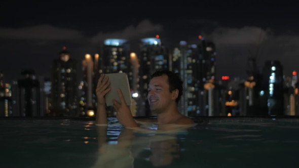 Man With Pad In Rooftop Pool Of Night Kuala Lumpur
