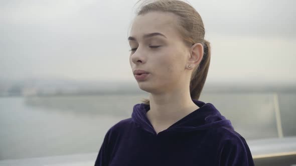 Closeup of Young Slim Woman Sighing Outdoors on Cloudy Overcast Day