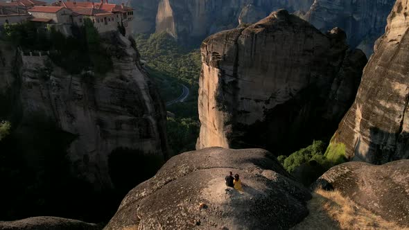 Couple Travelers Sitting on the Rocks Looking at Meteora Templates in Greece