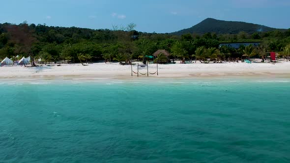 Aerial pan along white sand beach with turquoise blue sea. Koh Rong, Cambodia