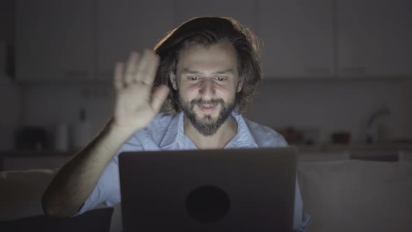 Relaxed Young Man with Beard Webchatting with Friend Via Laptop