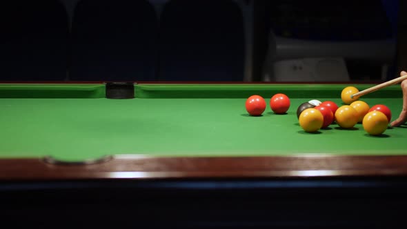 Potting a red ball in to a center pocket on a green pool table in a bar