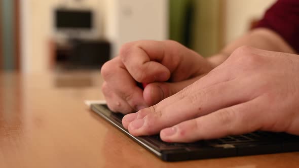 A Man Uses a Special Stencil and Stylus to Write a Letter in Braille