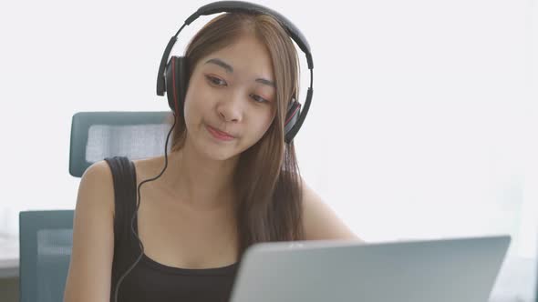 Asian girl wear headphones or headset to study online or home work on computer notebook 