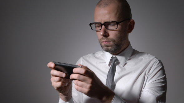 A Businessman Or a Middle-aged Manager In Glasses Holding a Smartphone In The Hands And Prints In