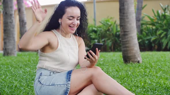 European Woman Makes an Online Video Call Using a Smartphone Via Headphones Conferencing on the