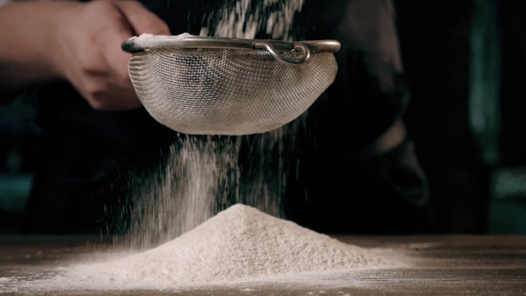 Chief's Hands Sifting Flour Through a Sieve For Baking