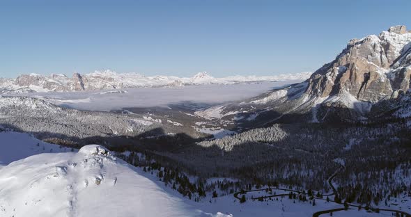 Backward Aerial to Snowy Valley with Woods Forest and Road at Valparola Pass