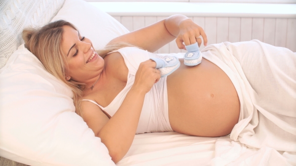 Pregnant Woman Playing With Baby Booties On Belly