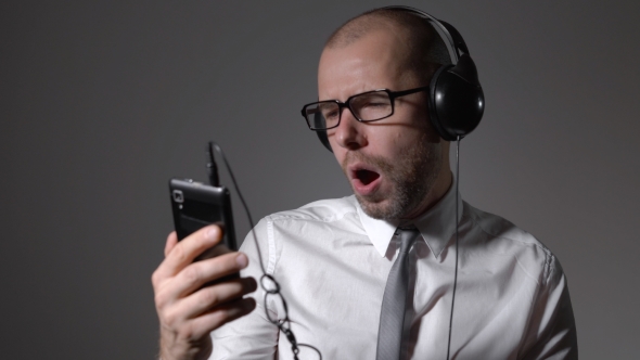 Businessman In a Shirt And Big Headphones, Singing In a Smartphone, Uses An Application.
