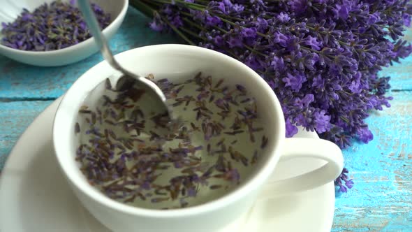 Tea from fresh lavender flowers on a vintage wooden background. Tea is brewed in hot water in a cup.