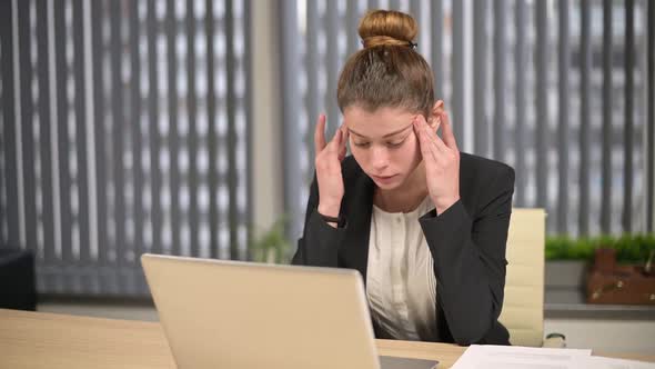 A young female office worker is overwhelmed with work