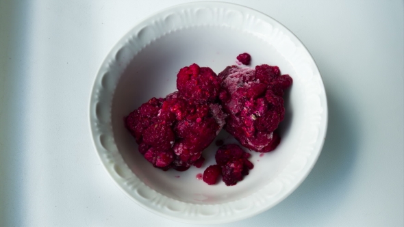 Frozen Raspberries Melting In a Plate On a White Background.