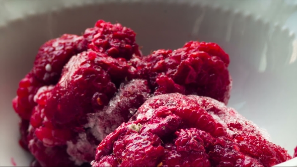 Frozen Raspberries Melting In a Plate On a White Background.