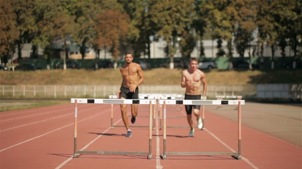 Two Athlets Run On Short Distance With Hurdles At The Stadium