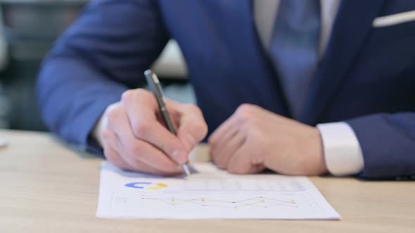 Close Up of Hands of Businessman Writing on Paper