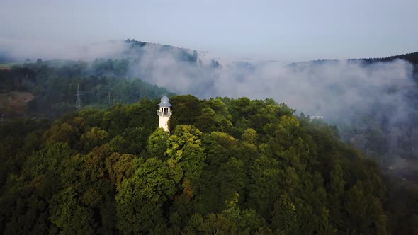 Flying above tower in forest with train behind