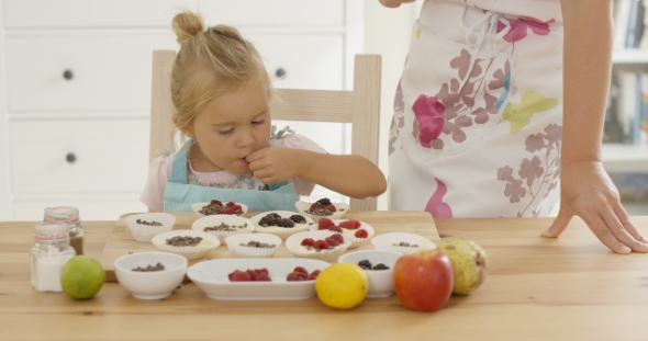 Cute Little Girl Putting Berries On Muffins