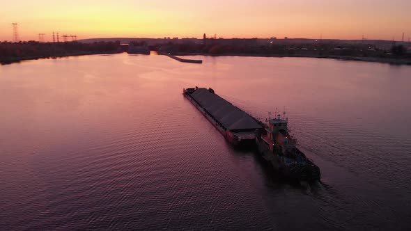Aerial View. Sunset Over the Water Channel. The Cargo Barge Goes Towards the Locks. A Bulk Carrier