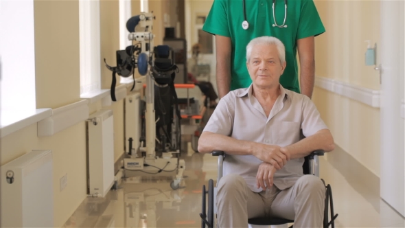 Doctor Pushes Wheelchair With Patient At The Hospital