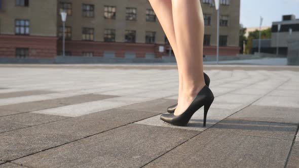 Slim Female Legs in Black Shoes on High Heels Walking at City Square on a Sunny Day. Feet of Young