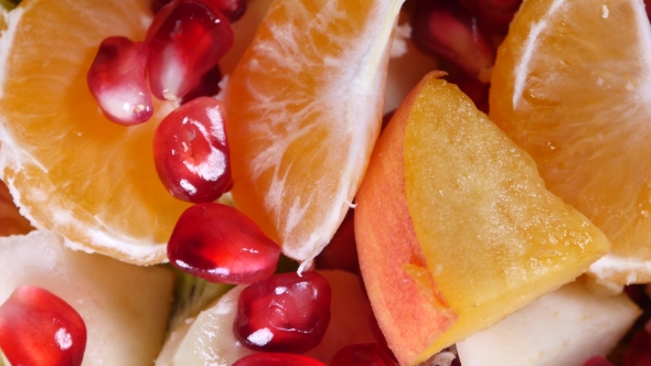 Top View Of a Fruit Salad With Mandarin, Oranges, Kiwi, Pomegranate Seeds, Figs, Banana And Peaches
