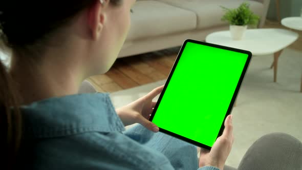 View From the Shoulder of Woman Using Hand Gestures on Green Mock-up Screen Digital Tablet Computer