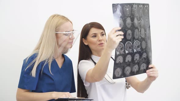 Two Young Doctors Looking At Computed Tomography Xray Image Discussing