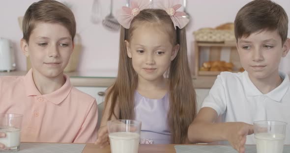 Close-up of Happy Children Clinking Glasses with Milk and Smiling. Portrait of Cheerful Little