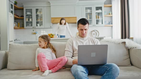 Confident Man Working on Laptop at Home but His Daughter Disturbing Him and Pushing Keyboard Buttons