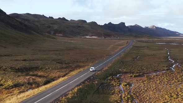 Small transporter van driving in remote valley on empty road in Iceland, aerial