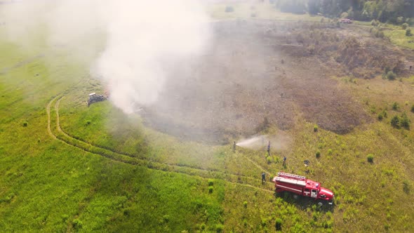 At the Edge of the Field a Fire Engine and a Fireman are Putting Out the Fire