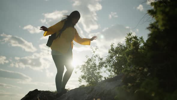 A Girl on a Hike in the Mountains Walks Along Dangerous Rocks