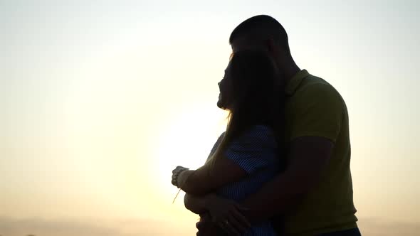 Guy Hugs His Girlfriend From Behind Against Sunset in Summer, Close-up in Slow Motion. Romantic Date