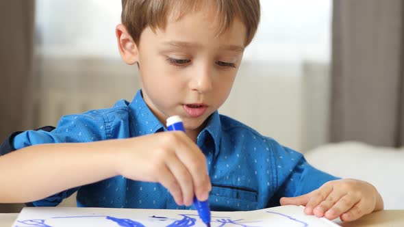 A Little Boy Sits at a Table and Paint a Bright Felt-tip Pen To a Happy Family