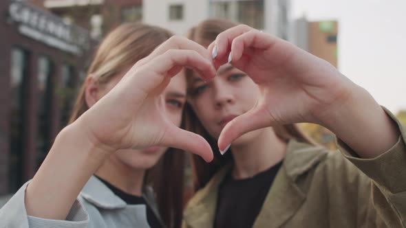 Portrait of Twin Sisters Showing Hand Heart