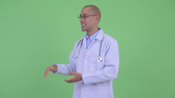 Happy Bald Multi Ethnic Man Doctor Presenting Something