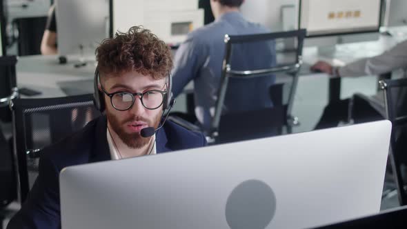 Close Up Portrait of a Technical Customer Support Specialist Talking on a Headset While Working on a