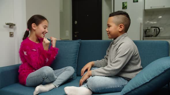 Multiethnic Boy and Girl Giving High Five Laughing Together at Home