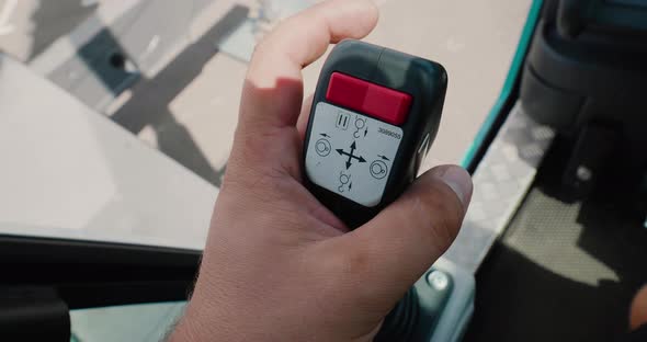 Close-up of a mobile crane operator's hand holding a joystick to control a crane mechanism.