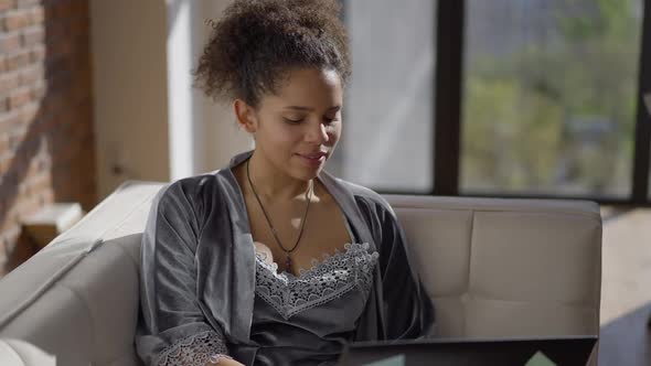 Young Slim Charming Woman Sitting on Couch Conferencing Online From Home Office