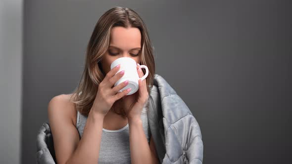 Pleasant Domestic Woman Smiling Drinking Tea in Wrapped Blanket