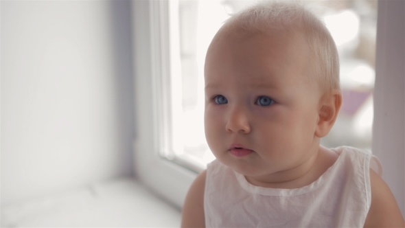 Cute Little Baby Girl Looking Into The Camera And Seat Near Window alt